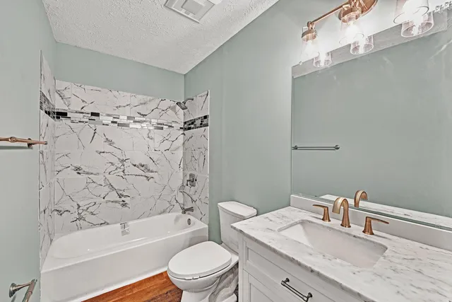 a bathroom with a granite countertop sink a toilet and shower