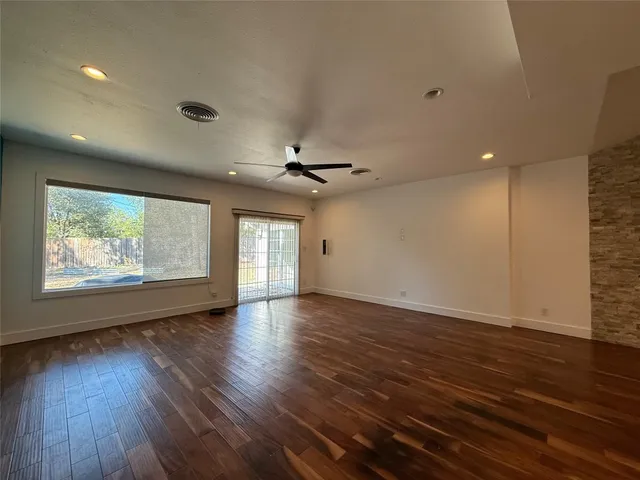 an empty room with wooden floor chandelier and windows