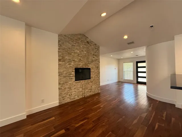 a view of an empty room with wooden floor and a fireplace