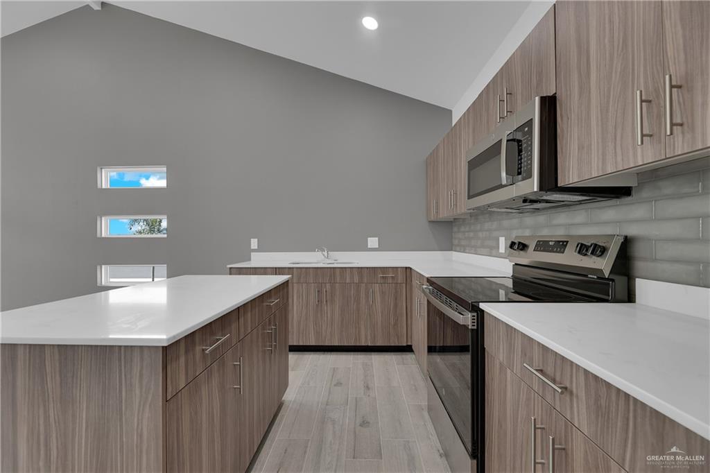 2509 Mockingbird Road, Unit B Weslaco, TX 78596 - Photo 4 of 11 Kitchen featuring stainless steel appliances, sink, high vaulted ceiling, and light hardwood / wood-style floors
