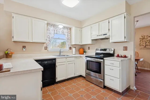 a kitchen with granite countertop white cabinets stainless steel appliances a sink and a window