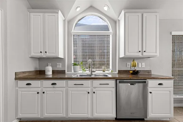 a kitchen with granite countertop white cabinets and a window