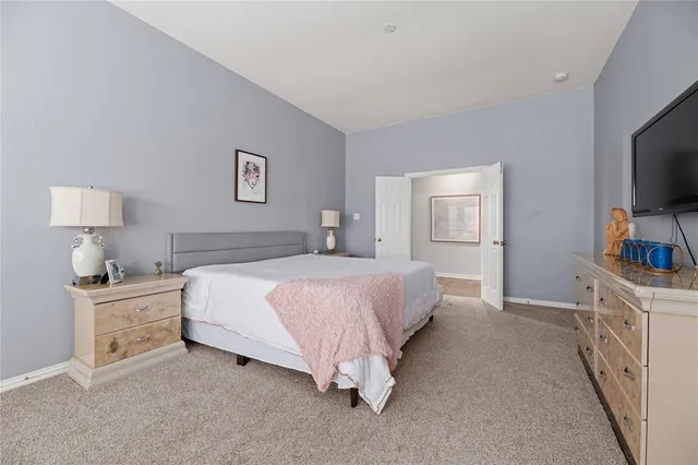 a spacious bedroom with a bed and a flat screen tv