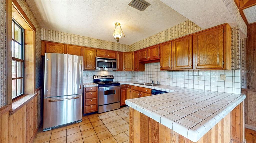 19803 Reading Road Lutz, FL 33558 - Photo 26 of 48 a kitchen with stainless steel appliances granite countertop a refrigerator a sink dishwasher a stove with wooden cabinets and floor