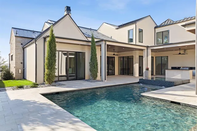 a view of a white house with a small yard plants and large tree