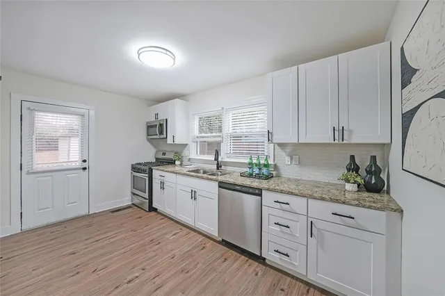 a kitchen with granite countertop white cabinets white appliances a sink and a window