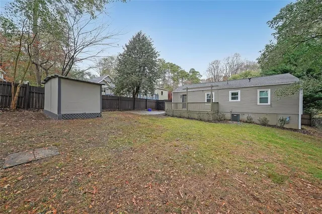 a backyard of a house with wooden fence and large trees