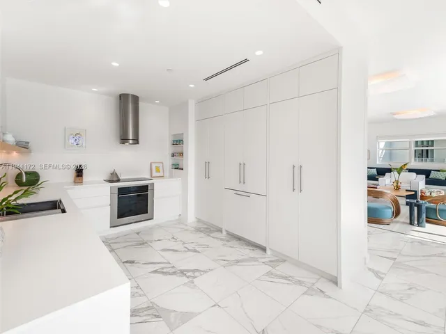 a kitchen with stainless steel appliances kitchen island granite countertop a refrigerator sink and white cabinets