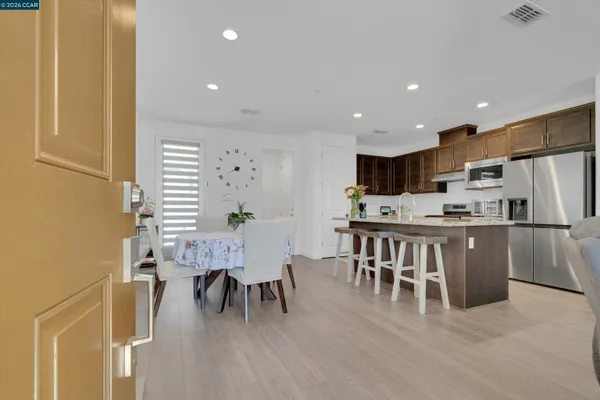 a kitchen with stainless steel appliances granite countertop a refrigerator a sink a stove a dining table and chairs