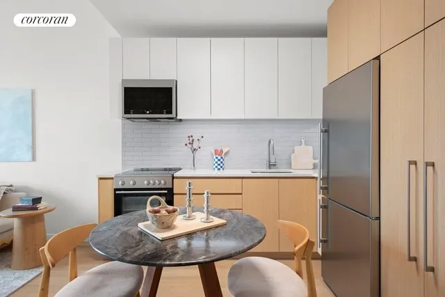 a kitchen with stainless steel appliances granite countertop a sink a microwave refrigerator and dining table