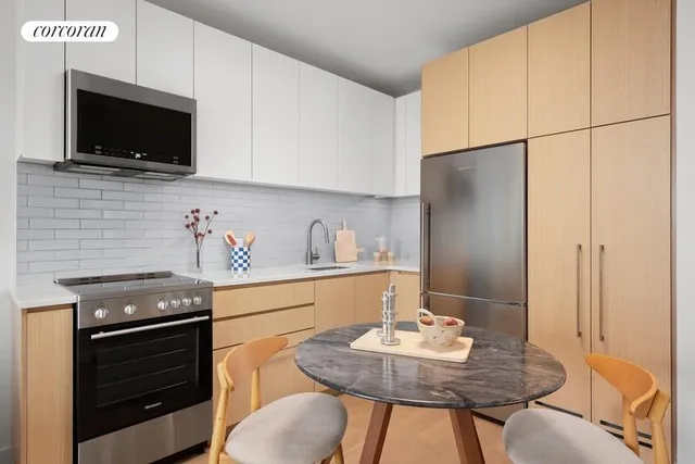 a kitchen with stainless steel appliances granite countertop a sink a stove a microwave a refrigerator and chairs