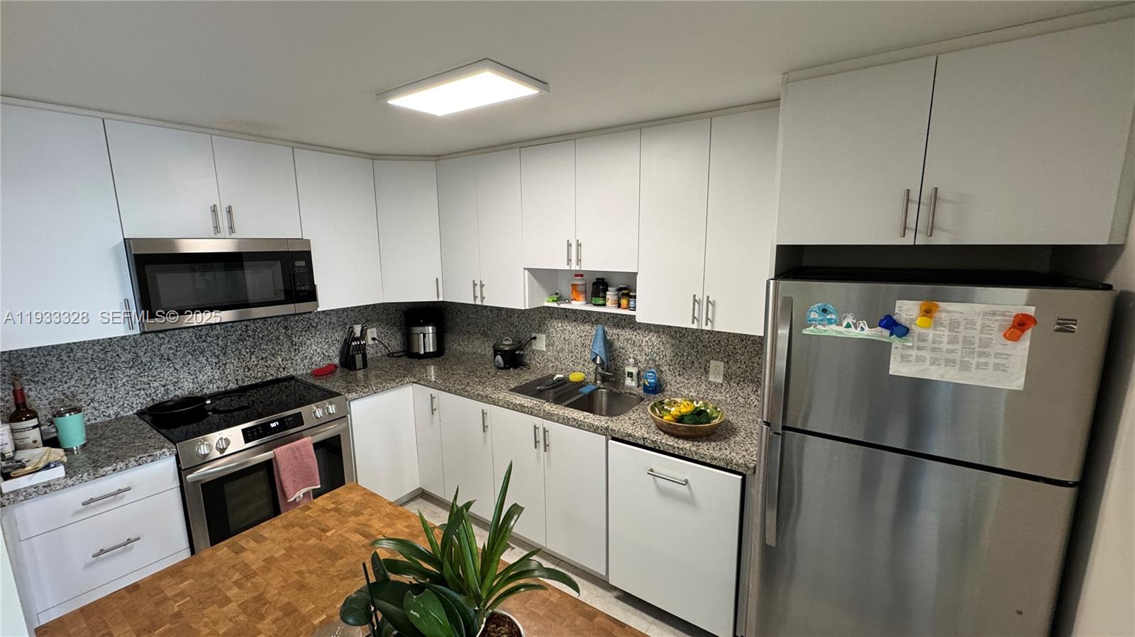 150 Southeast 25th Road, Unit 5L Miami, FL 33129 - Photo 2 of 9 a kitchen with stainless steel appliances a refrigerator sink stove and cabinets