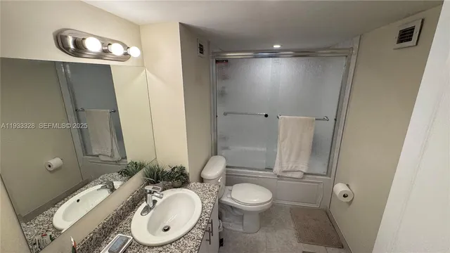a bathroom with a granite countertop sink toilet and shower