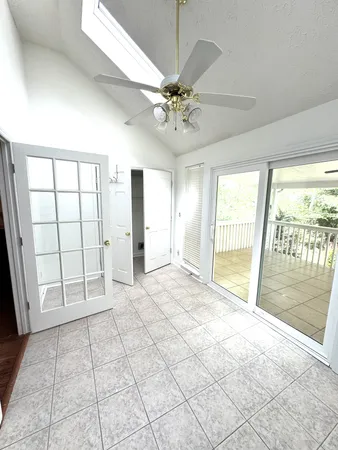 a view of an empty room with window and chandelier fan