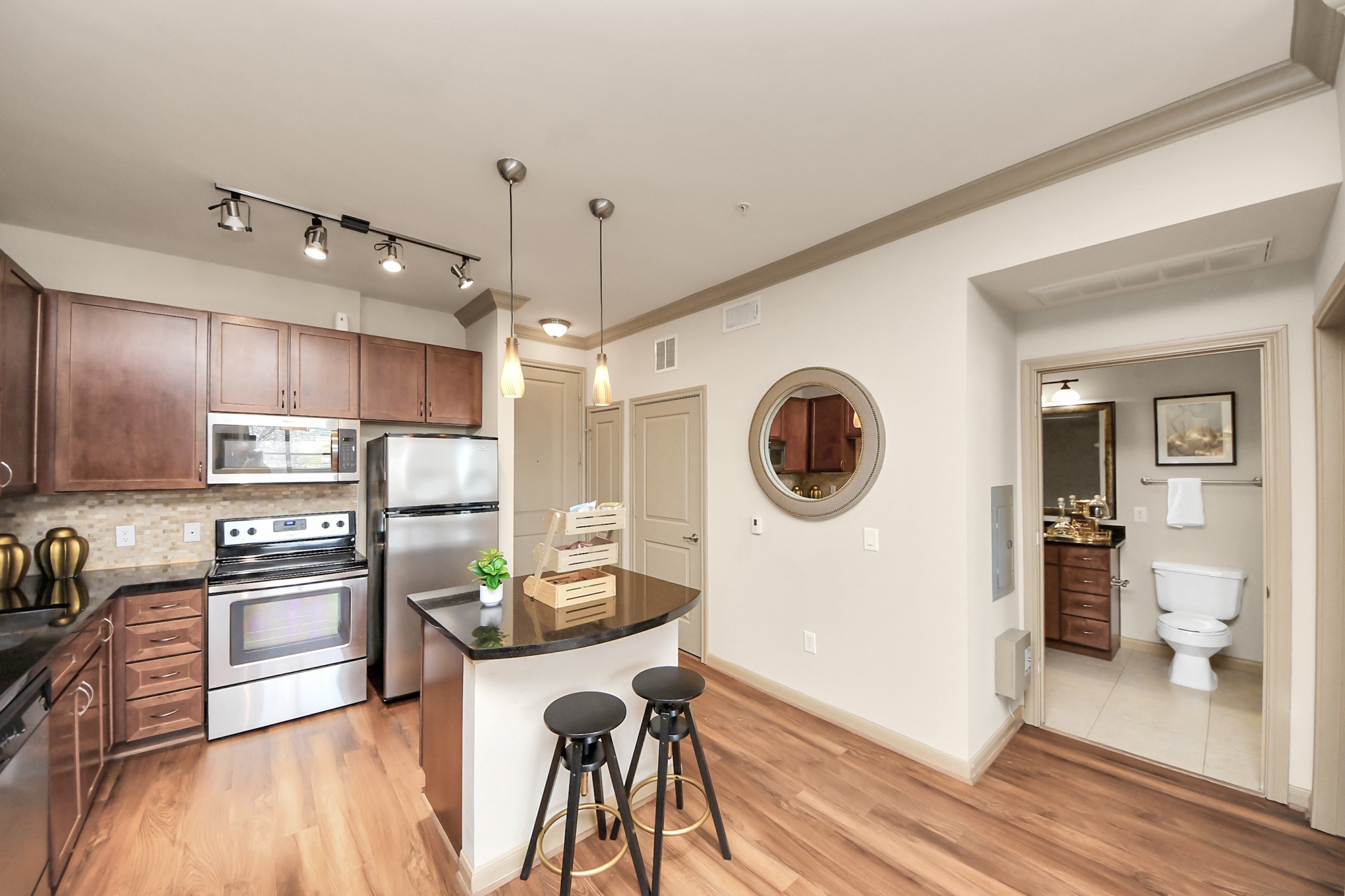 a kitchen with stainless steel appliances granite countertop a refrigerator a oven a sink a stove and white cabinets with wooden floor
