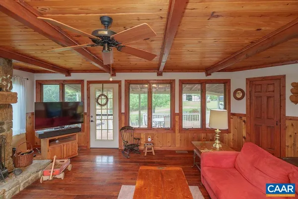 a living room with furniture a flat screen tv and floor to ceiling window