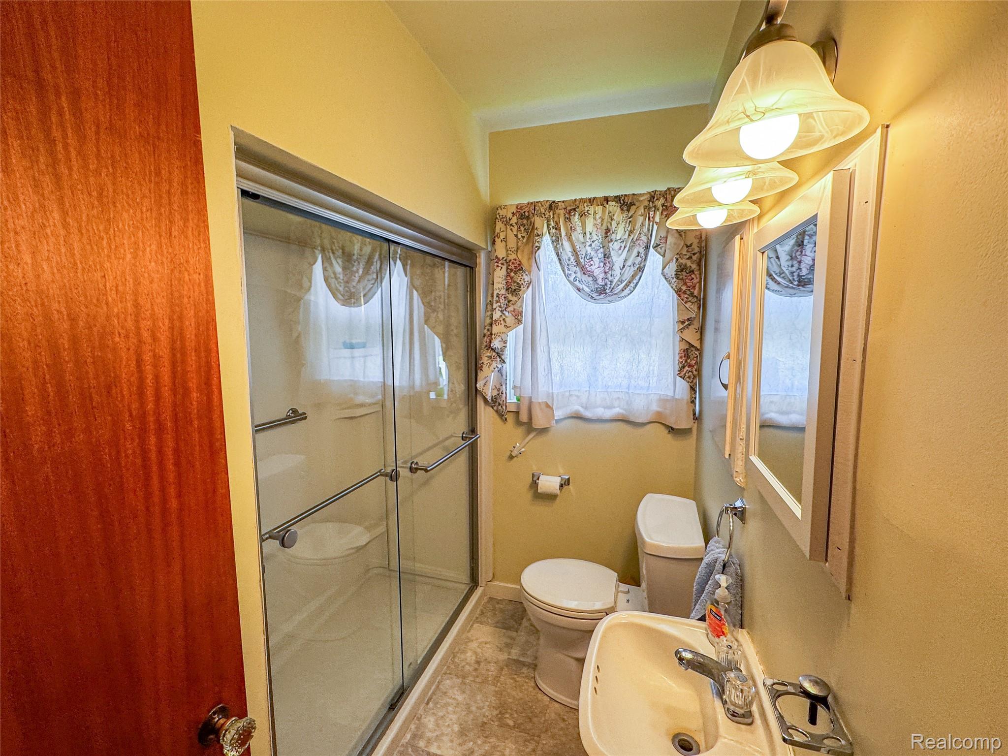 11651 South New Lothrop Road Byron, MI 48418 - Photo 6 of 19 Full bathroom featuring a sliding glass shower door, integrated grab bars, a single vanity, and wall-mounted light fixture