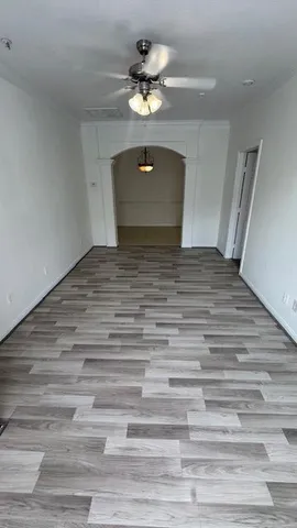 a view of a room with a ceiling fan and wooden floor