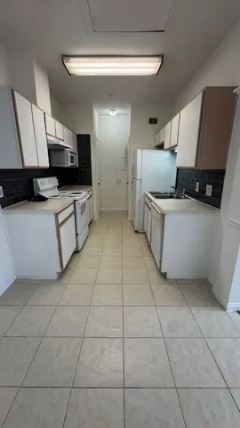 a large white kitchen with a stove a sink a microwave and a refrigerator