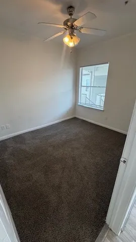 an empty room with windows and fan