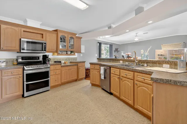 a kitchen with stainless steel appliances granite countertop a stove top oven a sink and dishwasher a refrigerator with wooden cabinets