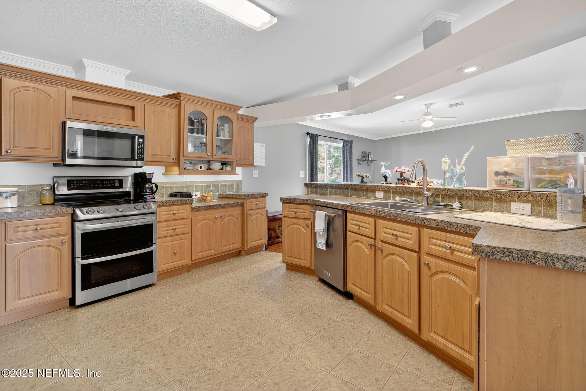 4824 Gadara Road Keystone Heights, FL 32656 - Photo 5 of 14 a kitchen with stainless steel appliances granite countertop a stove top oven a sink and dishwasher a refrigerator with wooden cabinets