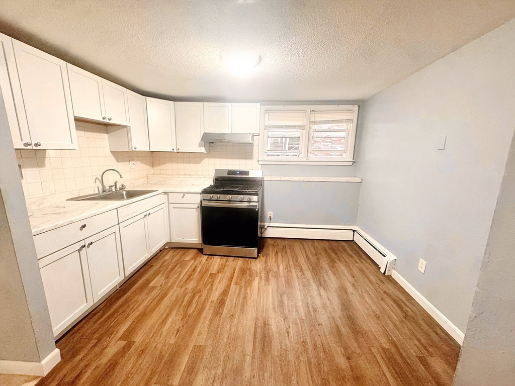 6 A Maynard Street, Unit A Boston, MA 02131 - Photo 8 of 12 a kitchen with wooden floors and white appliances
