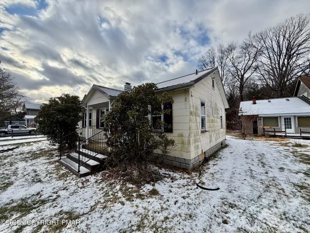 a view of a small white house and a yard covered with snow in the yard