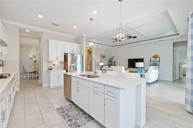 a kitchen with stainless steel appliances a sink dishwasher a refrigerator and a dining table with wooden floor
