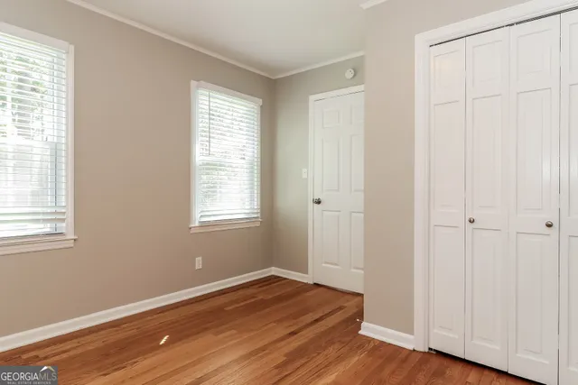 a view of an empty room with wooden floor and a window