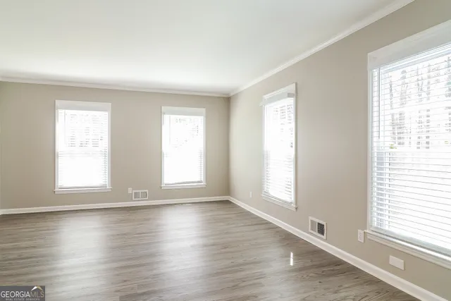 an empty room with wooden floor and windows with curtains view
