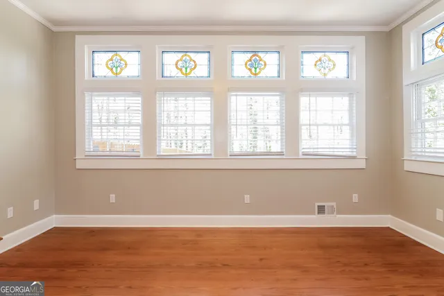 a view of an empty room with wooden floor and a window