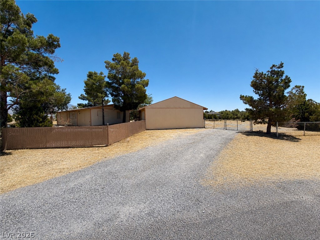 1611 West Blosser Ranch Road Pahrump, NV 89060 - Photo 2 of 25 A sprawling gravel driveway leads to a secluded property with ample open space.