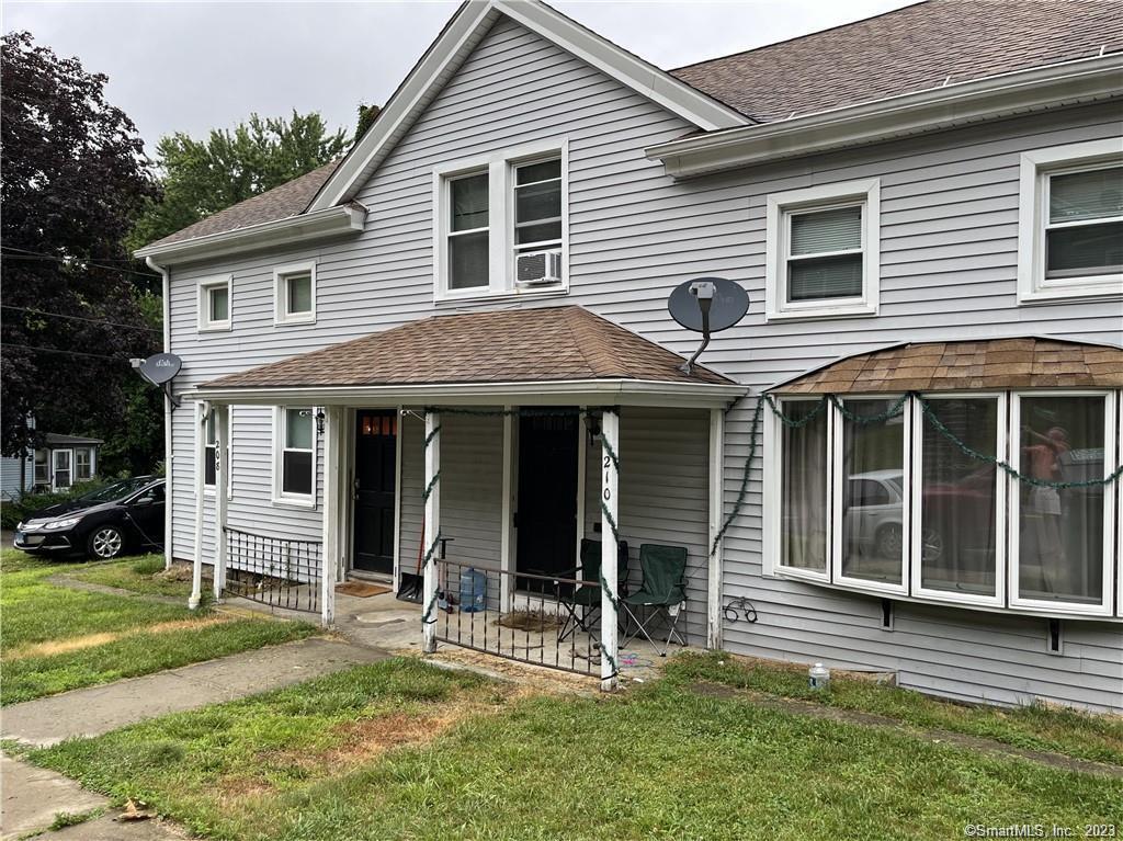 a view of a house with a yard and large tree