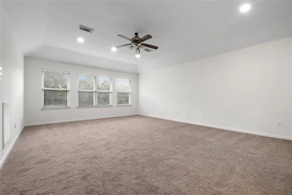 an empty room with windows and fan