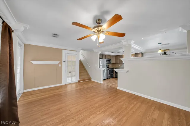a view of an empty room with a ceiling fan and wooden floor