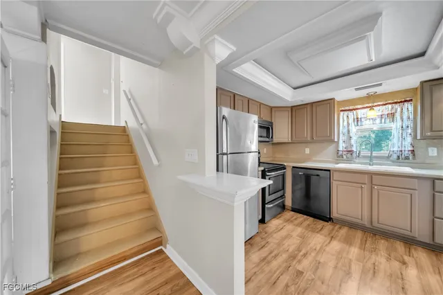 a kitchen with granite countertop a refrigerator a sink dishwasher a stove and white countertops with wooden floor