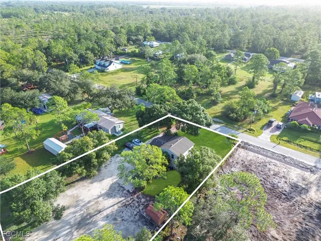 an aerial view of residential house with outdoor space and trees all around