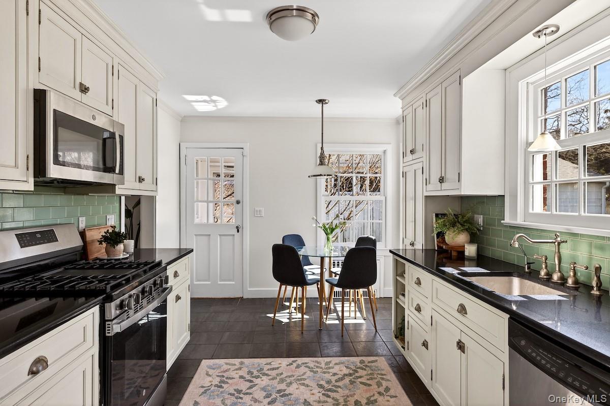 48 Fenwick Road Hastings-on-Hudson, NY 10706 - Photo 14 of 40 a kitchen with stainless steel appliances granite countertop a stove top oven a sink a dining table and chairs