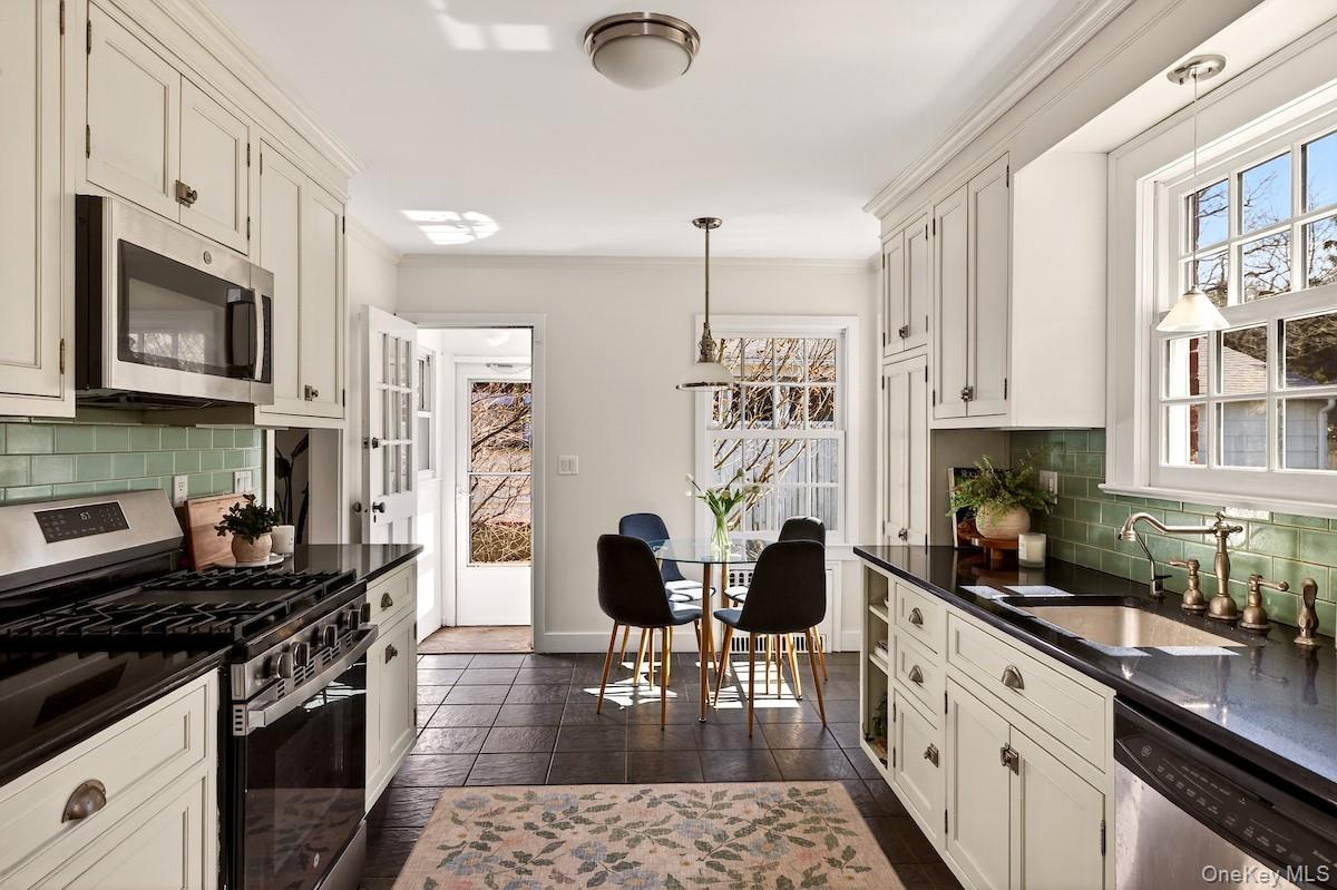 48 Fenwick Road Hastings-on-Hudson, NY 10706 - Photo 3 of 40 a kitchen with stainless steel appliances granite countertop a stove top oven a sink a dining table and chairs with wooden floor