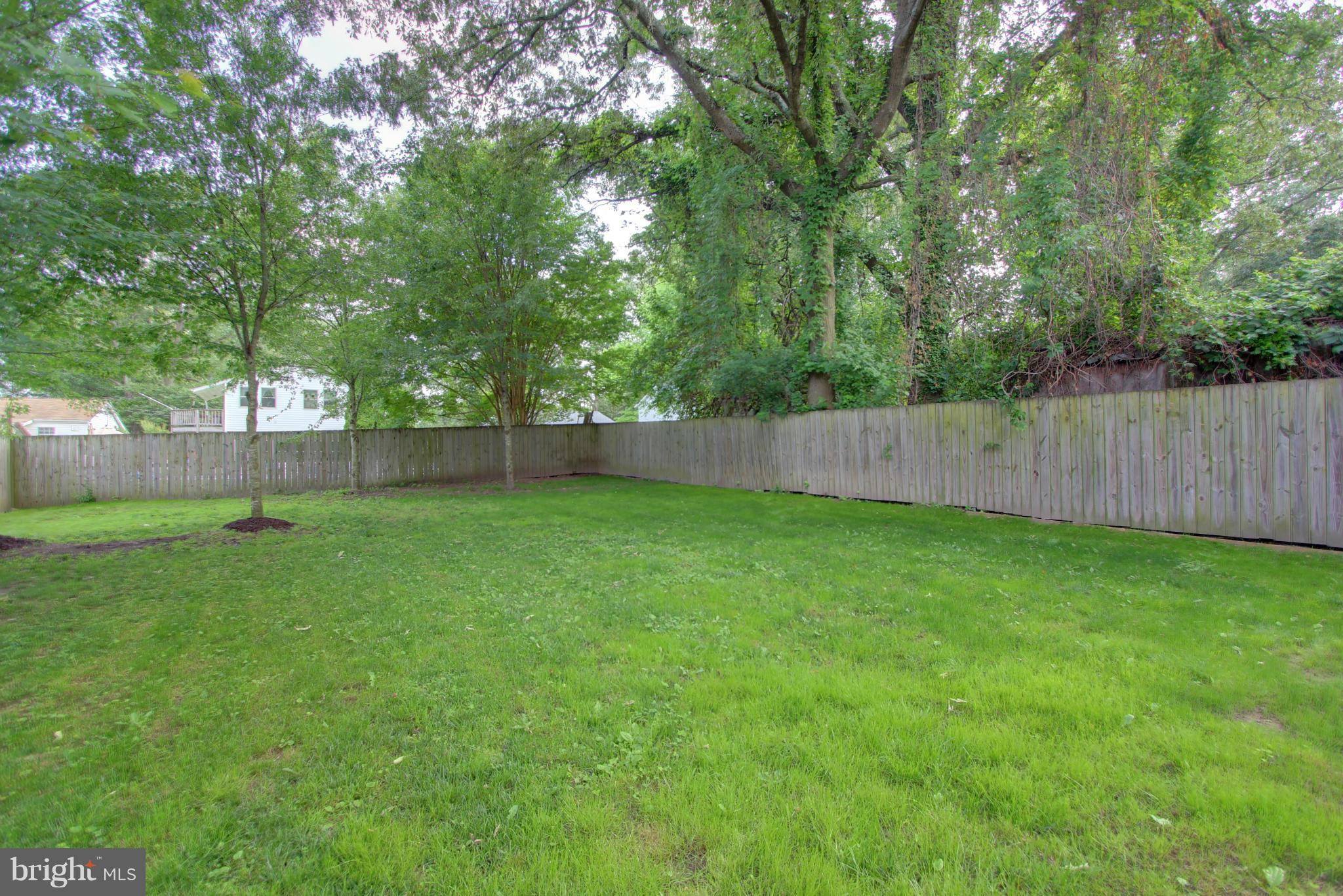 558 Sunset Knoll Road Pasadena, MD 21122 - Photo 4 of 30 a view of a backyard with a large tree and wooden fence