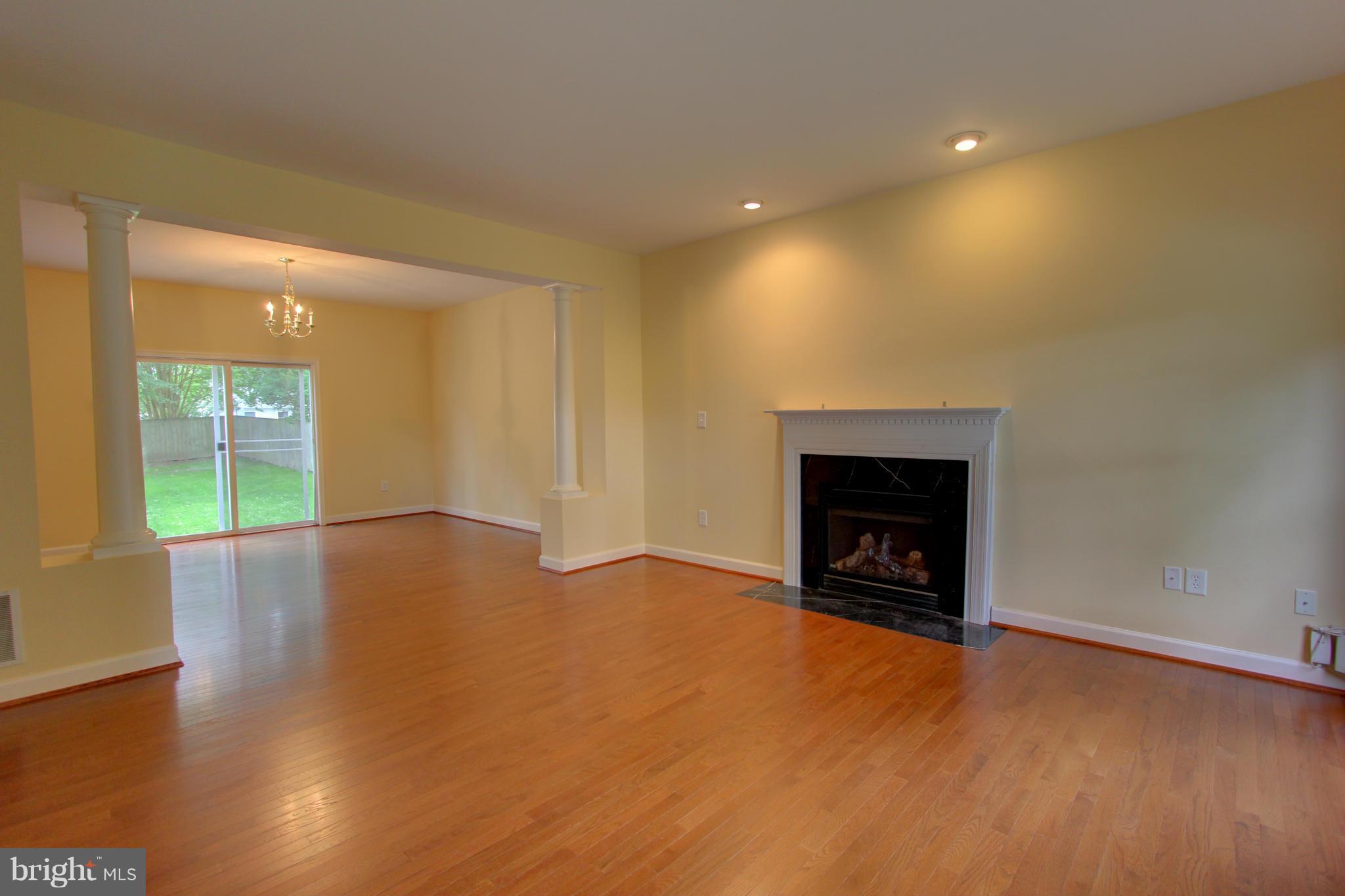 558 Sunset Knoll Road Pasadena, MD 21122 - Photo 5 of 30 an empty room with wooden floor fireplace and windows