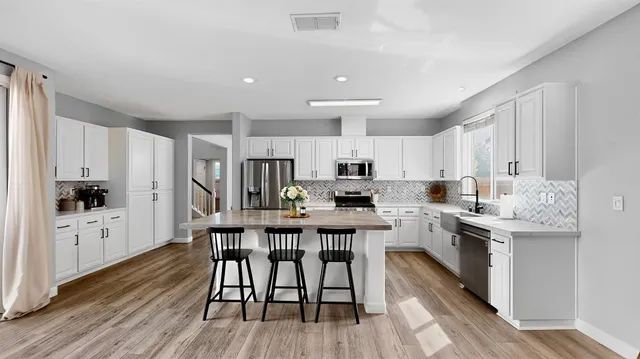 a kitchen with stainless steel appliances a dining table chairs microwave and sink