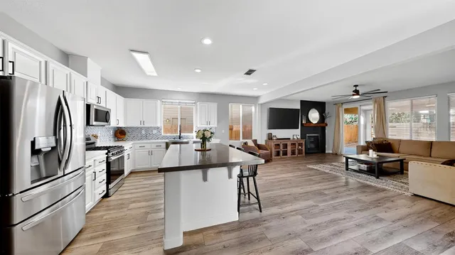 a living room with stainless steel appliances furniture refrigerator and kitchen