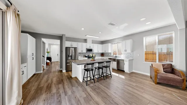 a living room with stainless steel appliances kitchen island granite countertop wooden floor a dining table and chairs