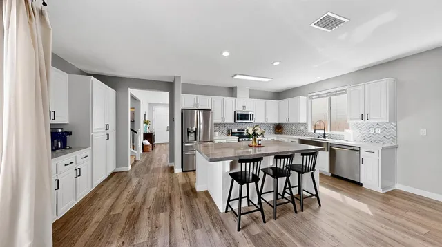 a kitchen with stainless steel appliances a dining table chairs and wooden floor