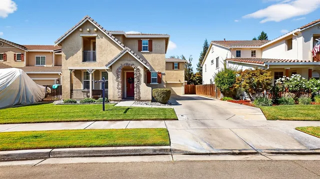 a front view of a house with a yard and potted plants