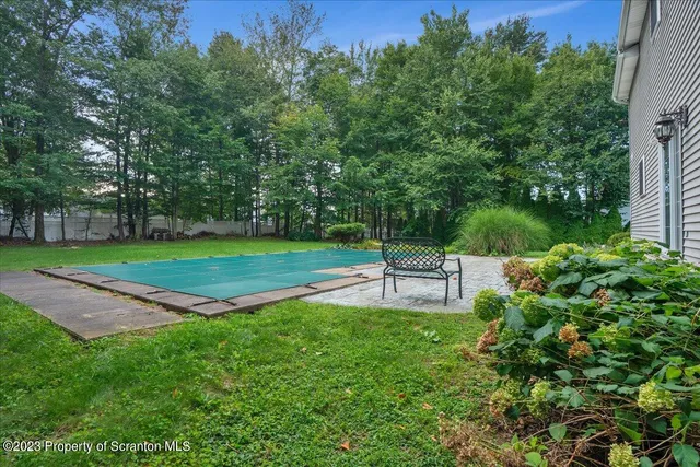a swimming pool with lots of green space and trees in the background