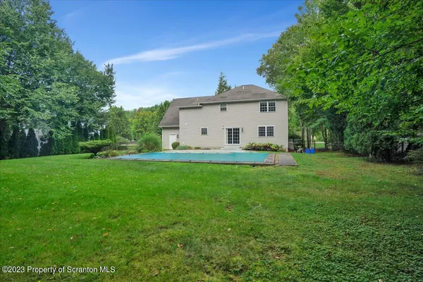 a white house with a small yard and big trees