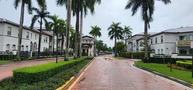 front view of a house with a yard and palm trees